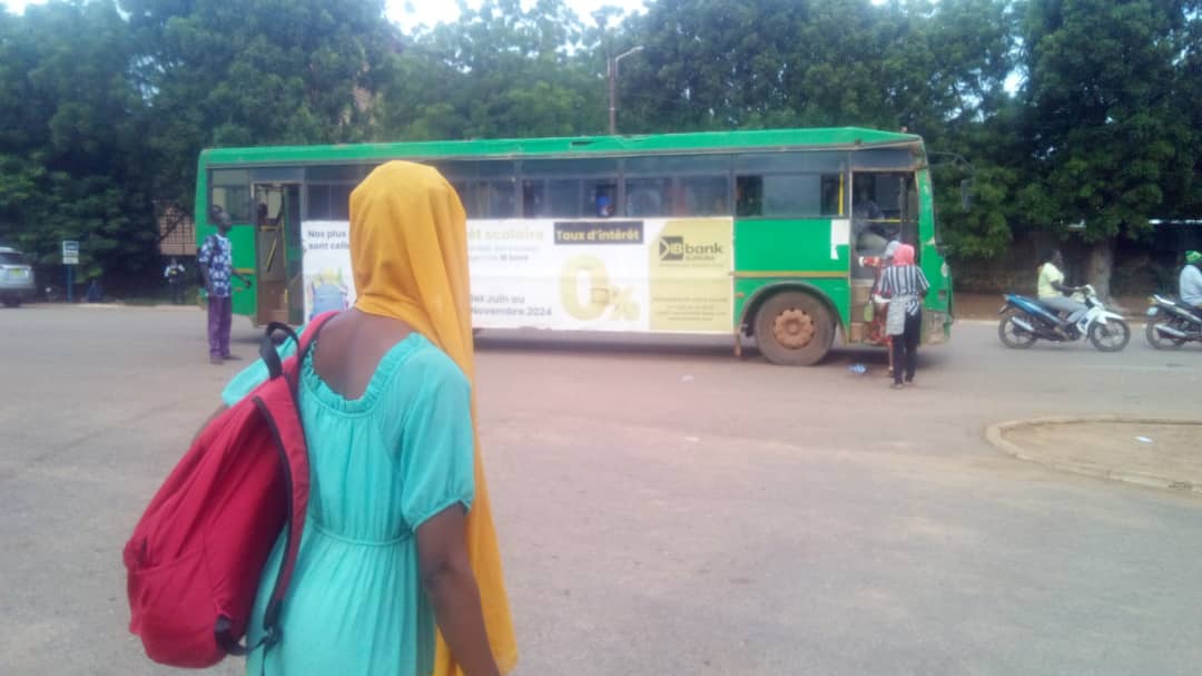 L'étudiante Elise Kagambega regardant partir un bus bondé